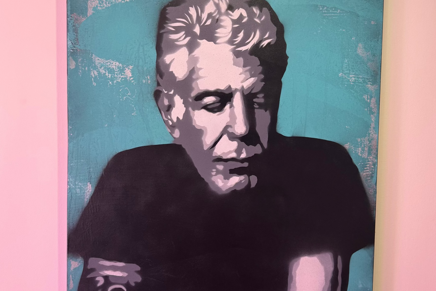 Canvas print of a stylized portrait of Anthony Bourdain on a pink wall.