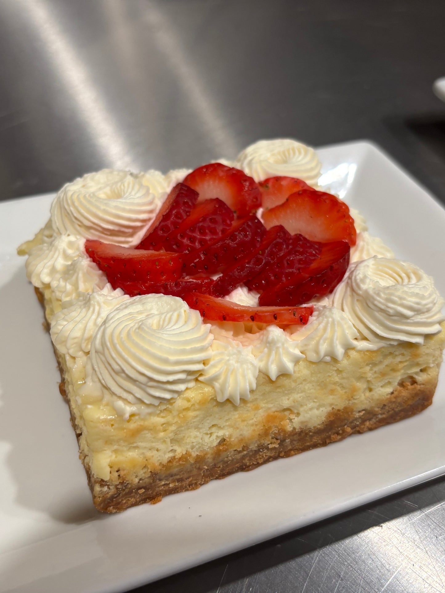 Cheesecake with strawberries and whipped cream on a white plate